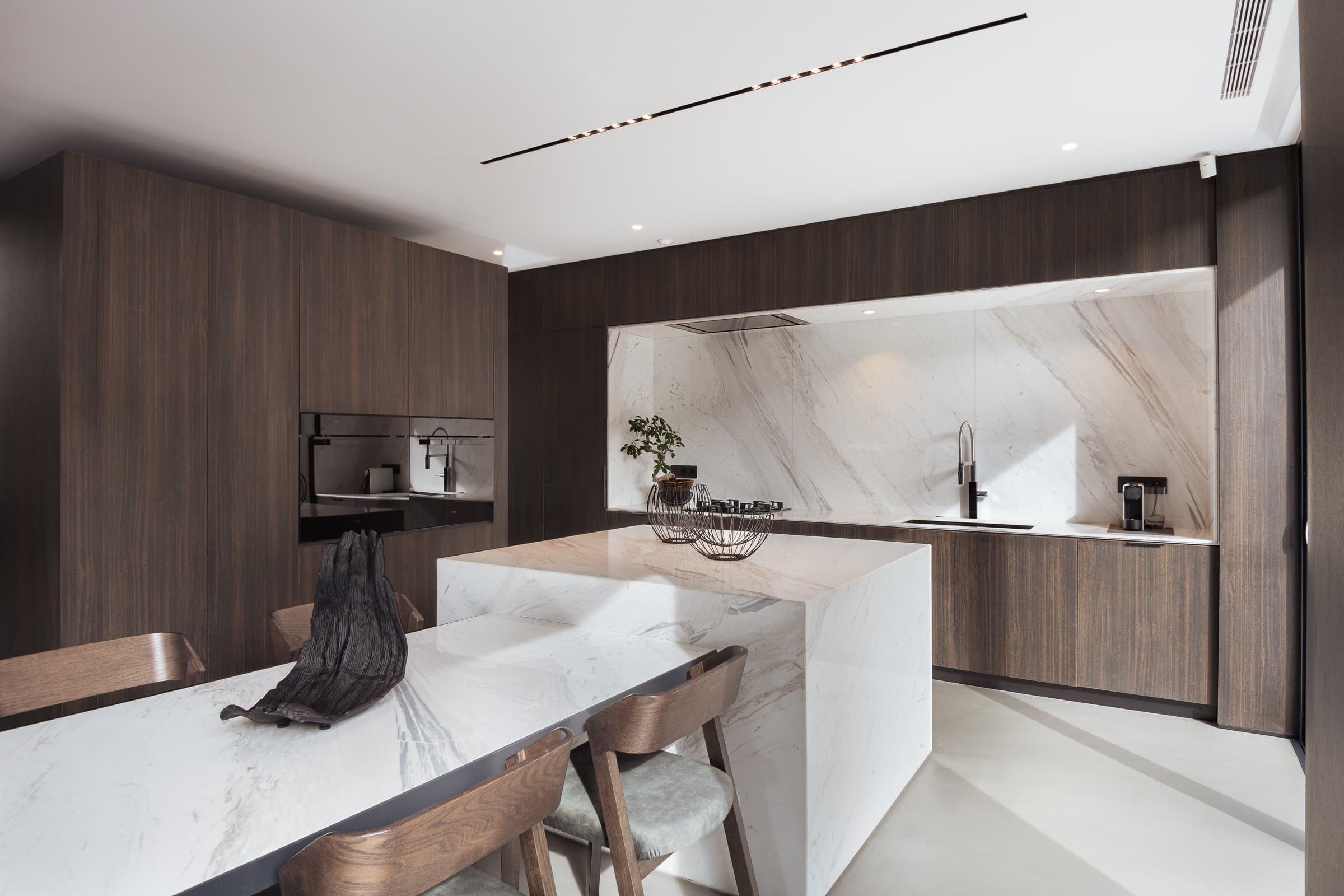 Kitchen with dark timber panelling and white marble island